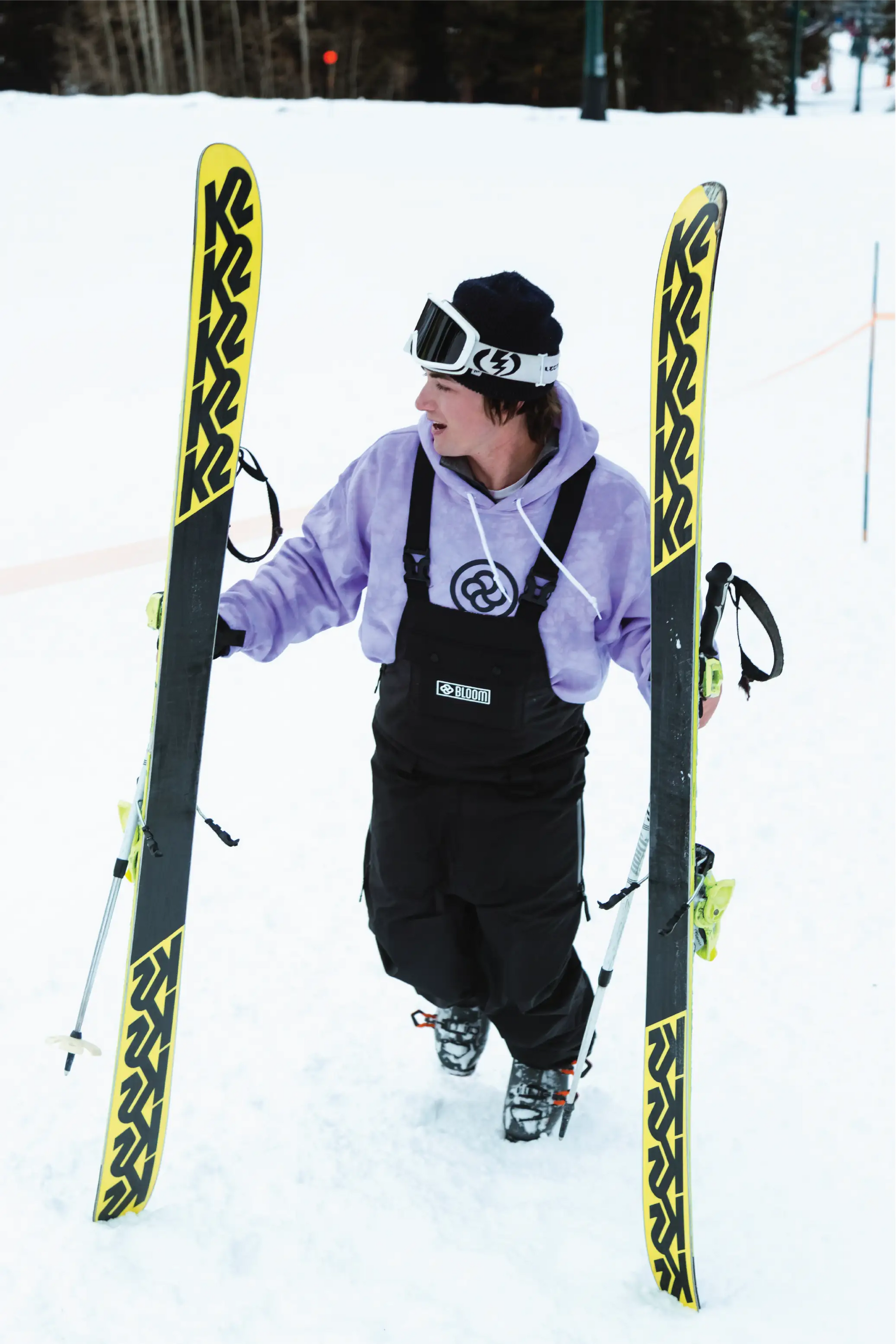 man walking up ski slope wearing baggy black snow bib