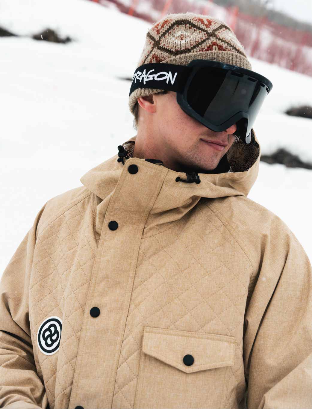 Man wears a baggy tan ski jacket on mountain slope
