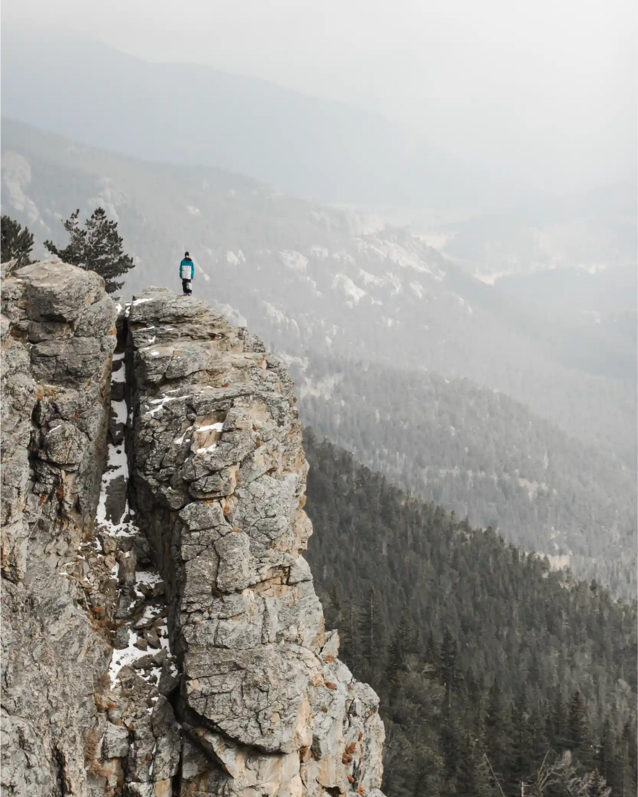 Man stands on cliff wearing the best ski wear brand