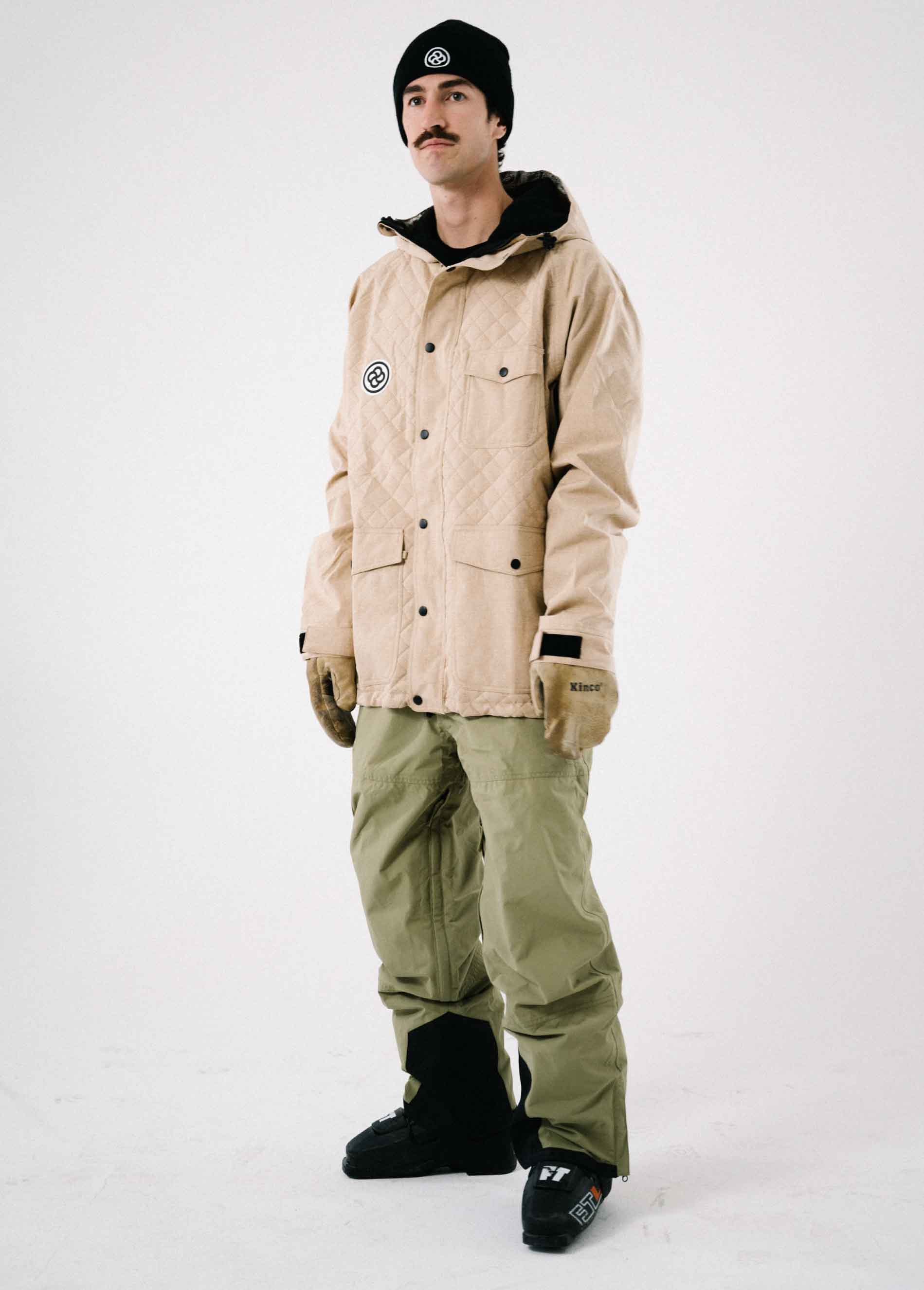 Man wears a cool tan ski jacket that is insulated and features a quilted pattern.