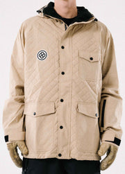 A man wearing a tan ski and snowboard jacket with quilted pattern, lots of pocket, and helmet compatible hood.