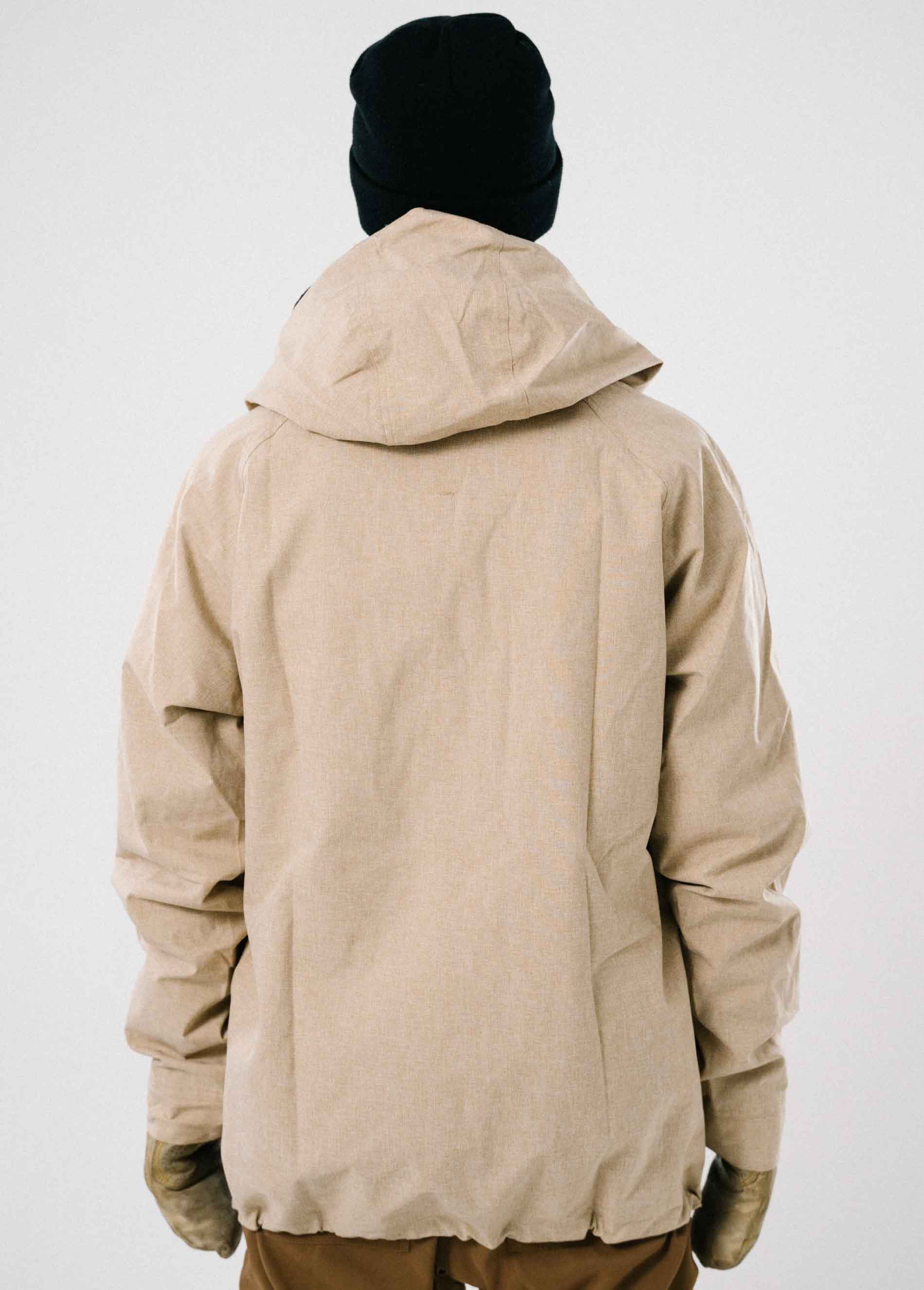 The back of a tan ski and snowboard jacket that is waterproof, insulated, and perfect for powder days.