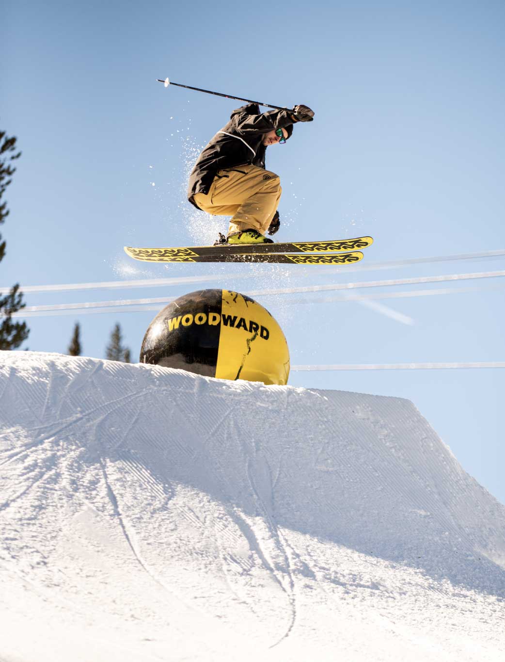 Man skis over rail wearing baggy anorak ski jacket