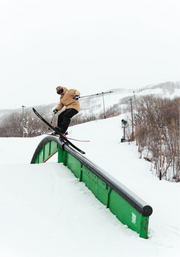Skier slides rail in a baggy ski jacket