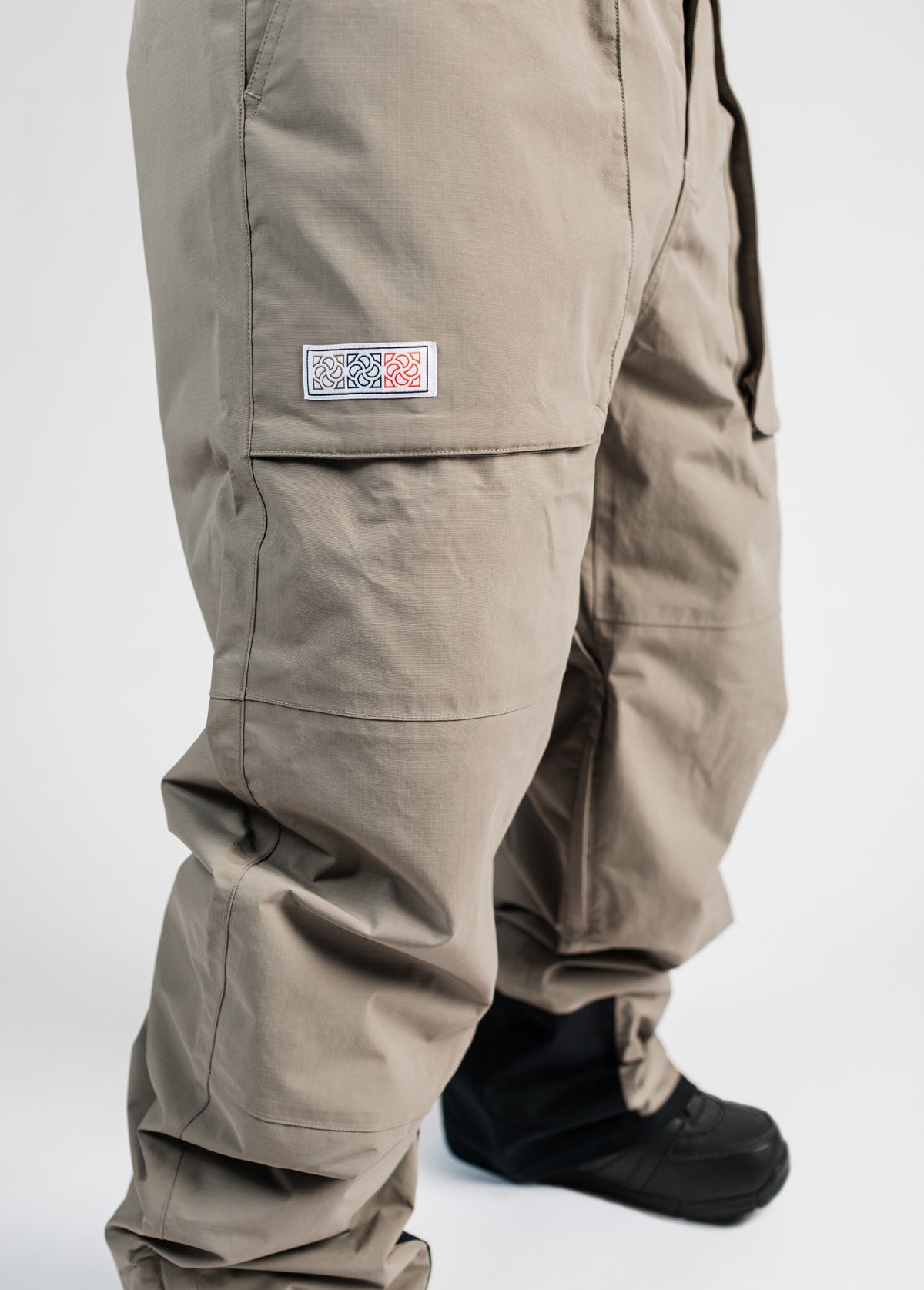 Woven branding label on taupe brown snowboarding pant with baggy fit