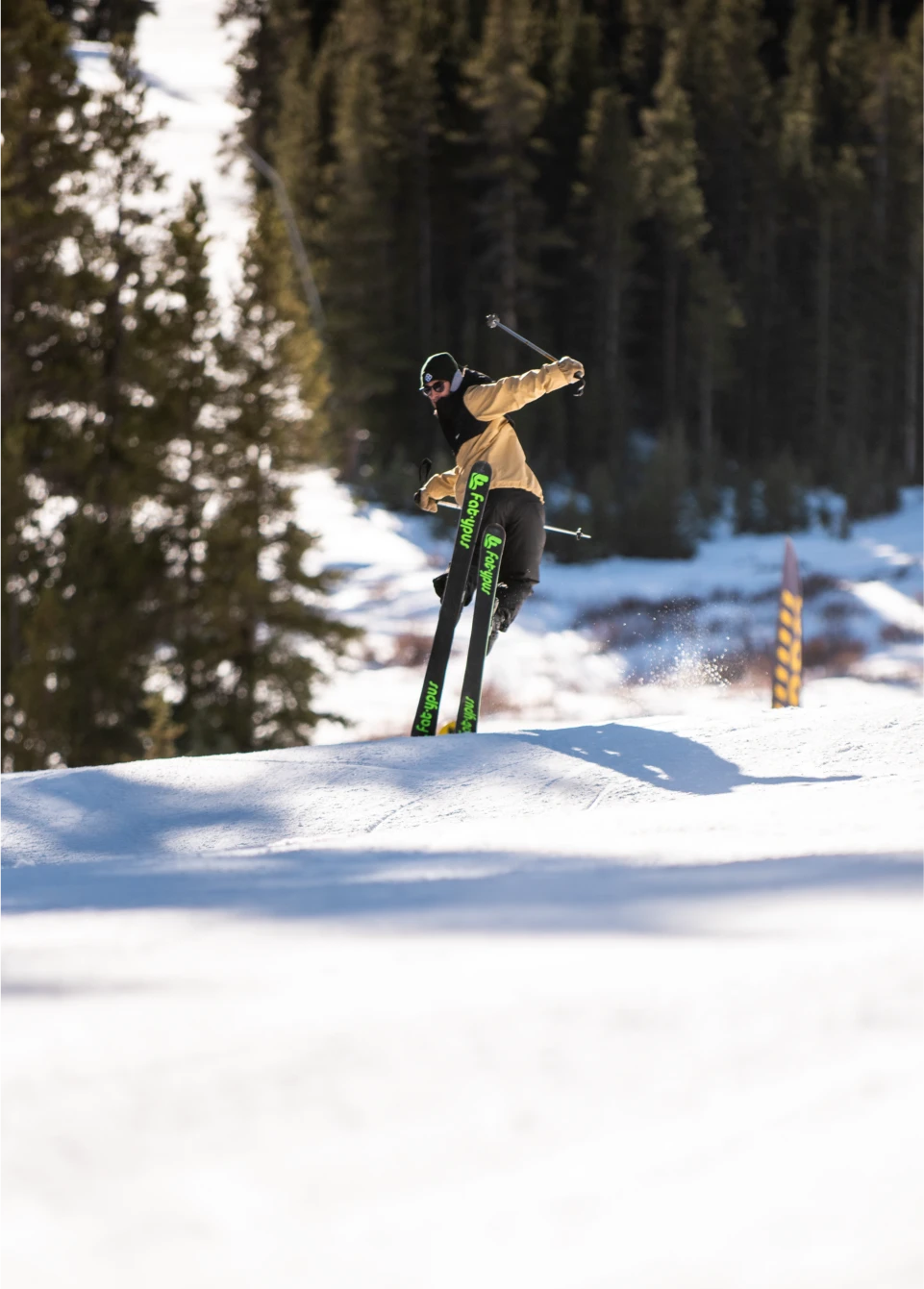 Park skier slides across slope on noses of his ski while wearing the best baggy ski pants for park