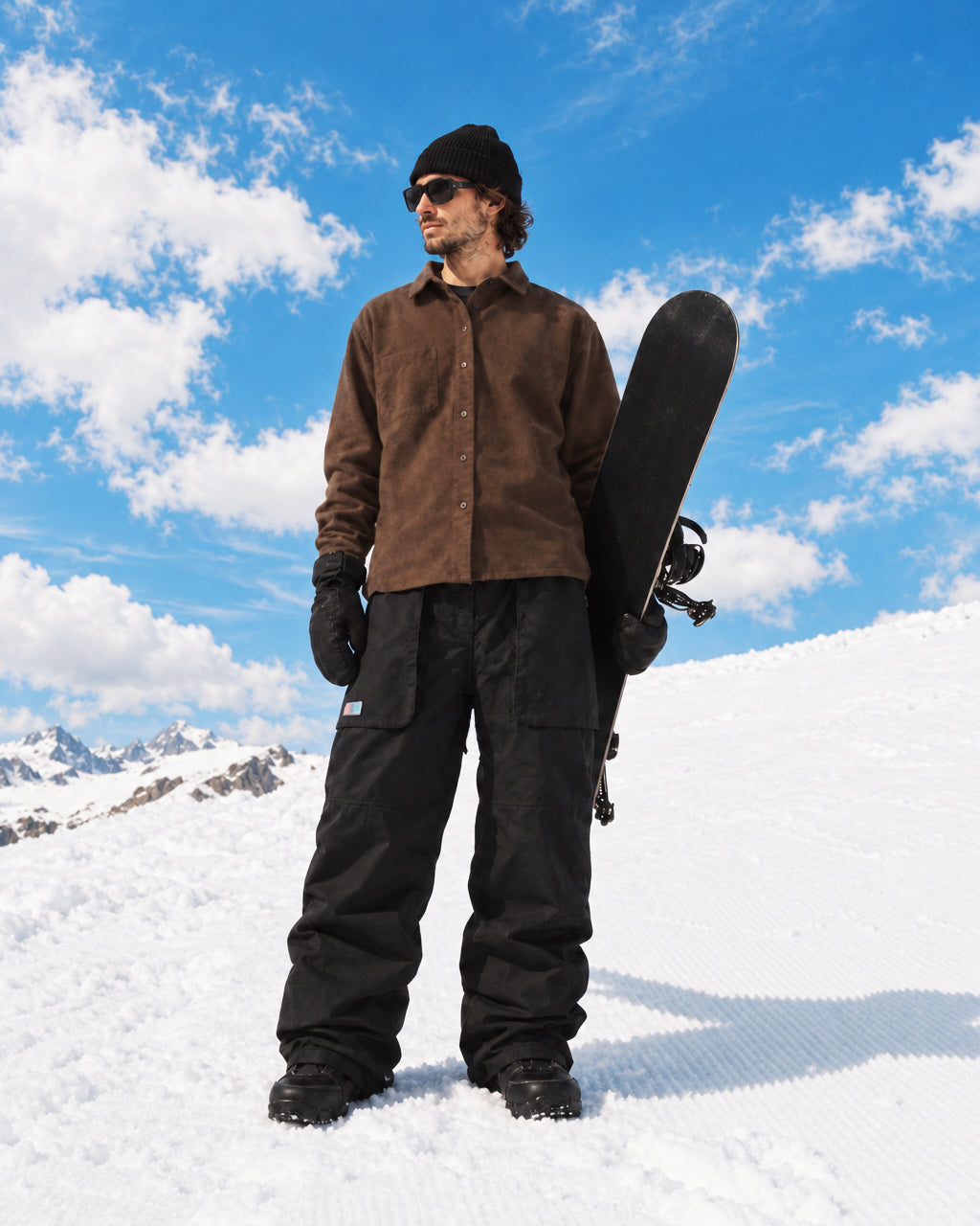 Snowboarder wearing baggy black snowboard pants on mountain slope
