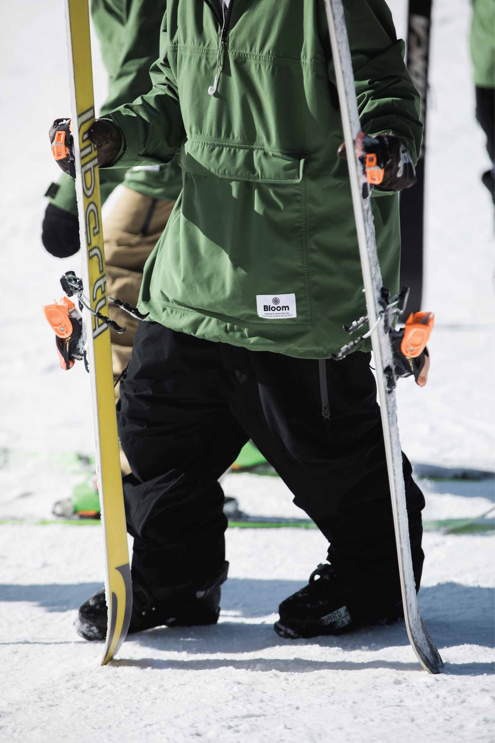 Skier wearing the best loose fit snow pant while he stands on slope with skis