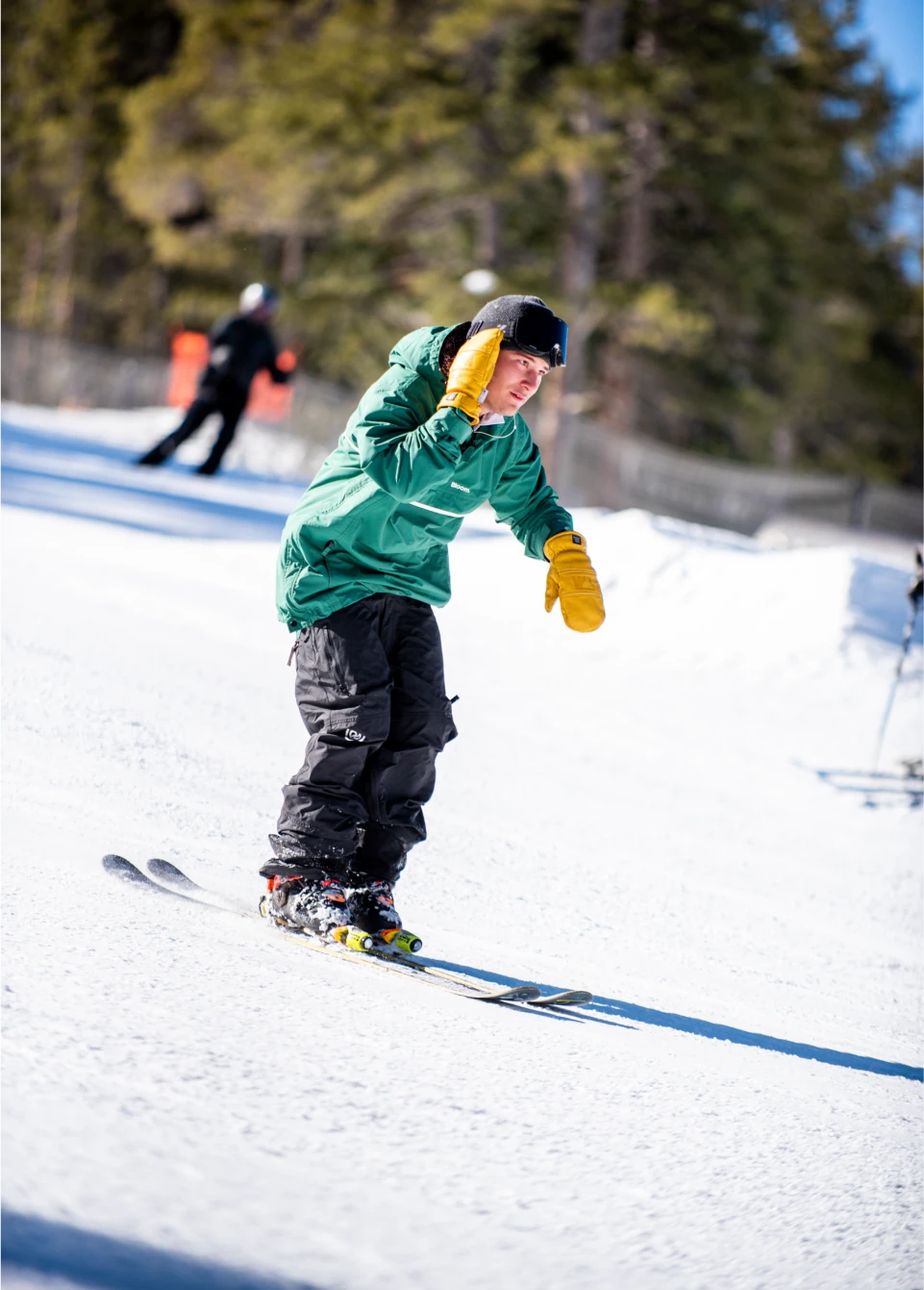 Park skier wearing a black baggy ski bib while skiing downhill