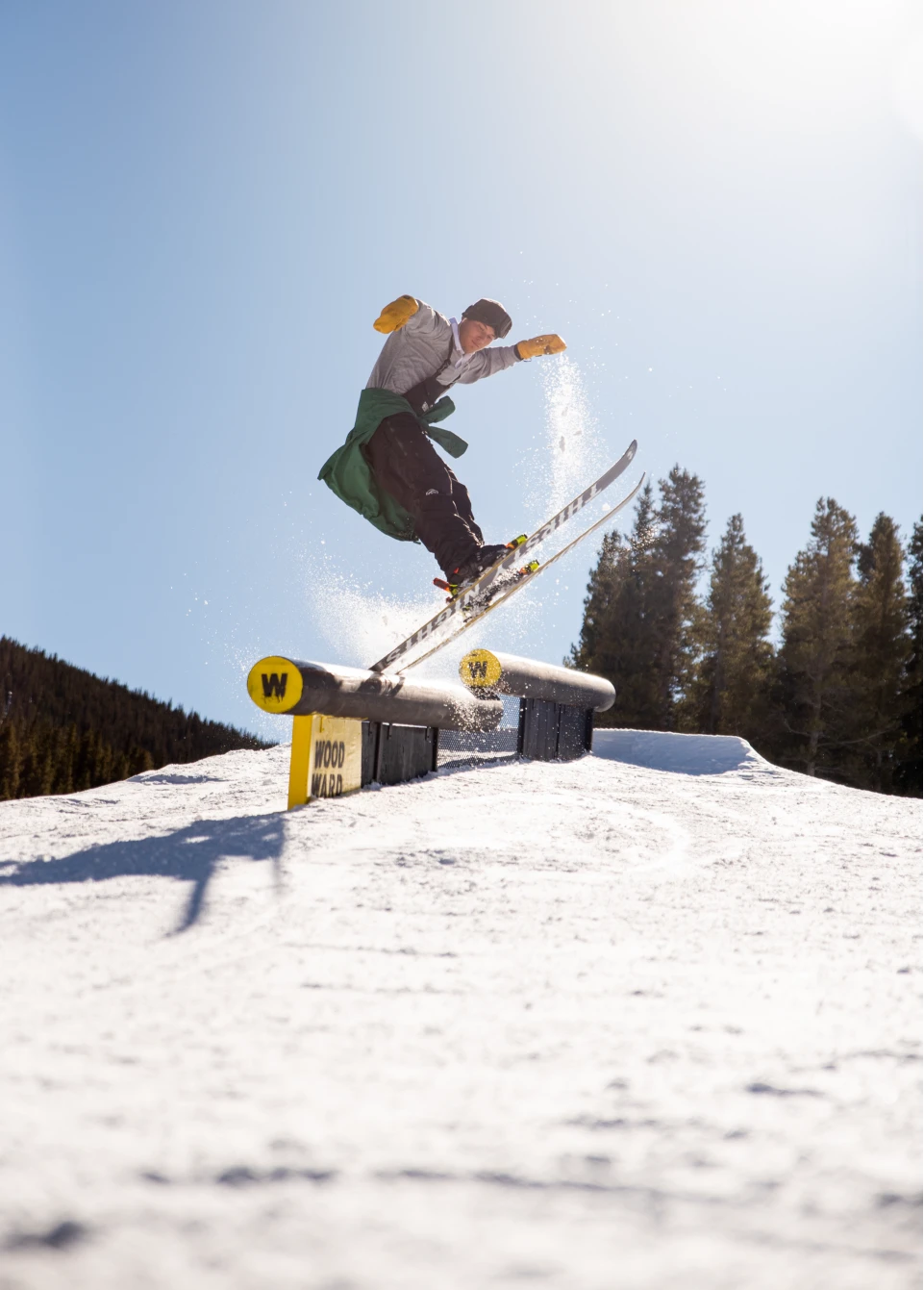 Skier wearing a black baggy ski bib while sliding a rail