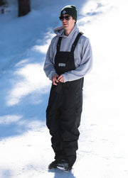 Snowboarder wearing a black baggy snowboard bib on a mountain slope