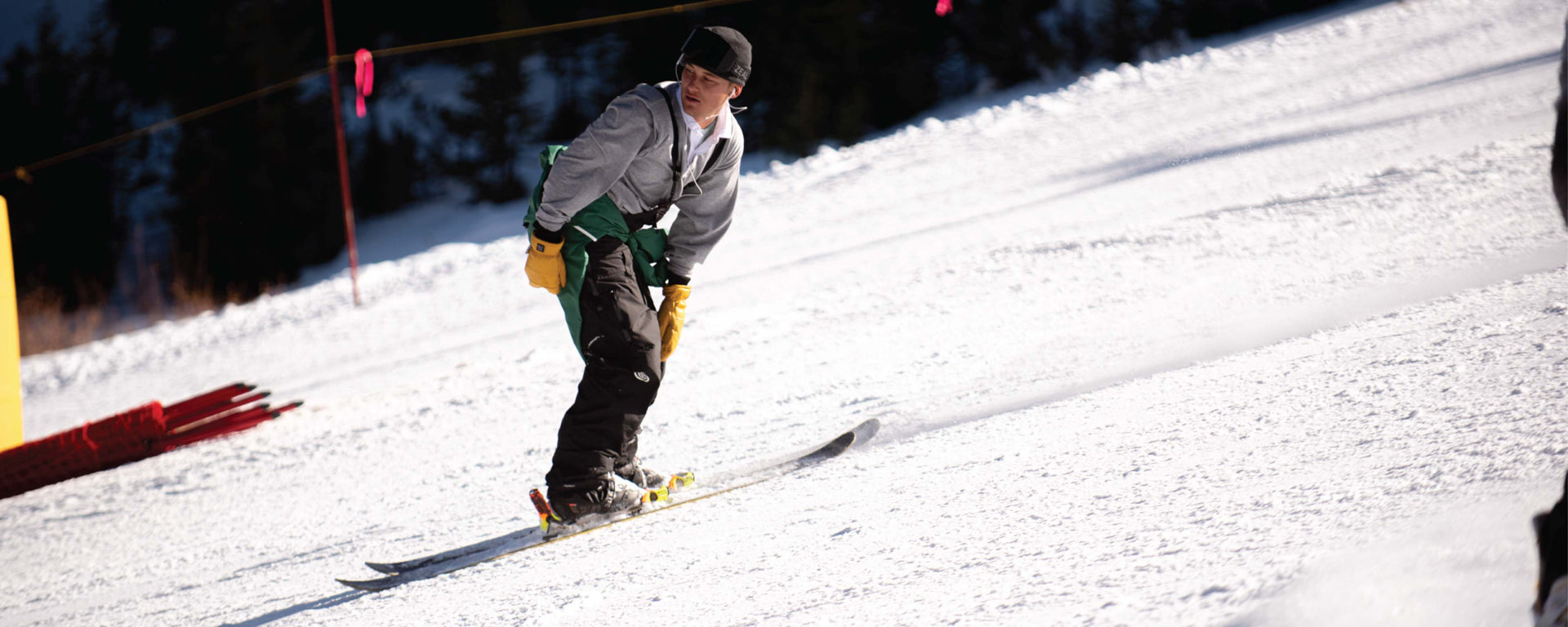 Man skiing backwards down a mountain slope wearing baggy ski pants