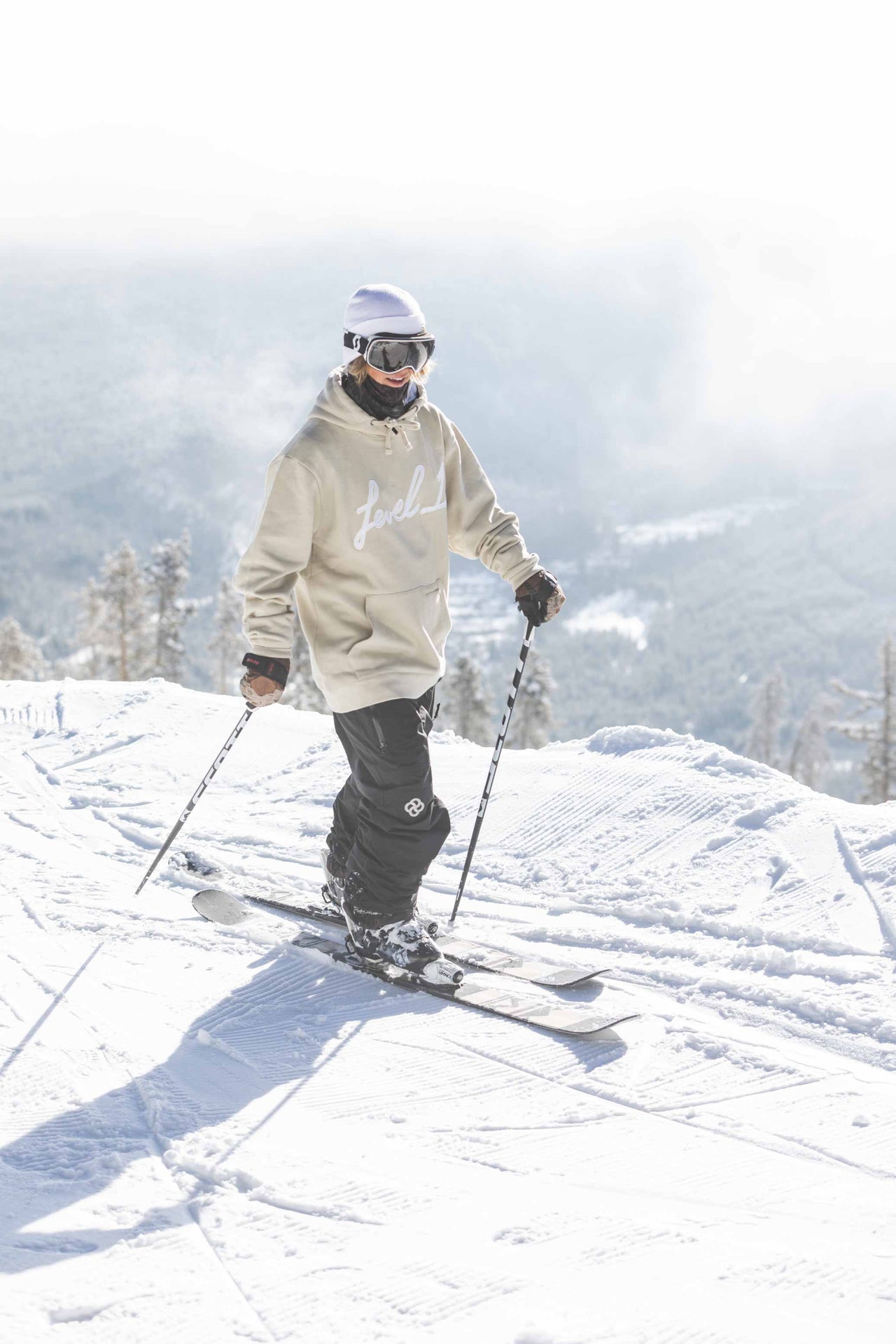 Man wearing baggy snow pants slides across mountain slope on skis with misty backdrop