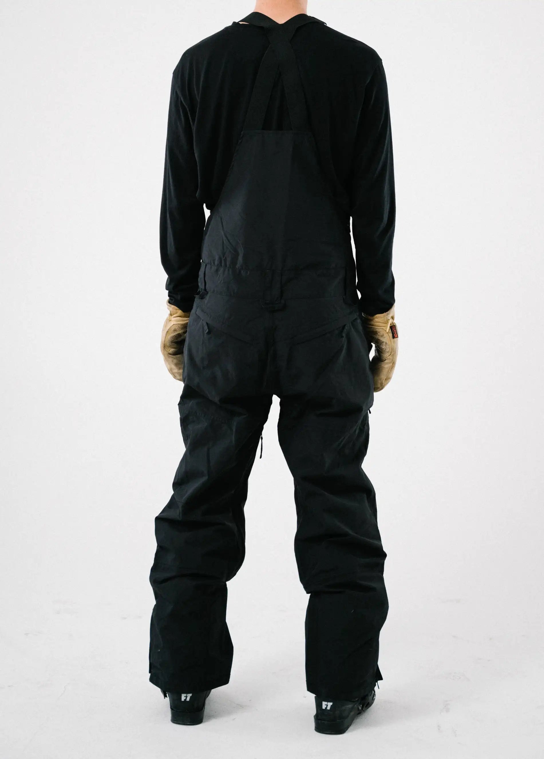 Back view of a lightweight black ski bib for men over white back drop