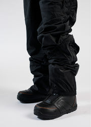Men's black snowboard bib worn over snowboard boots