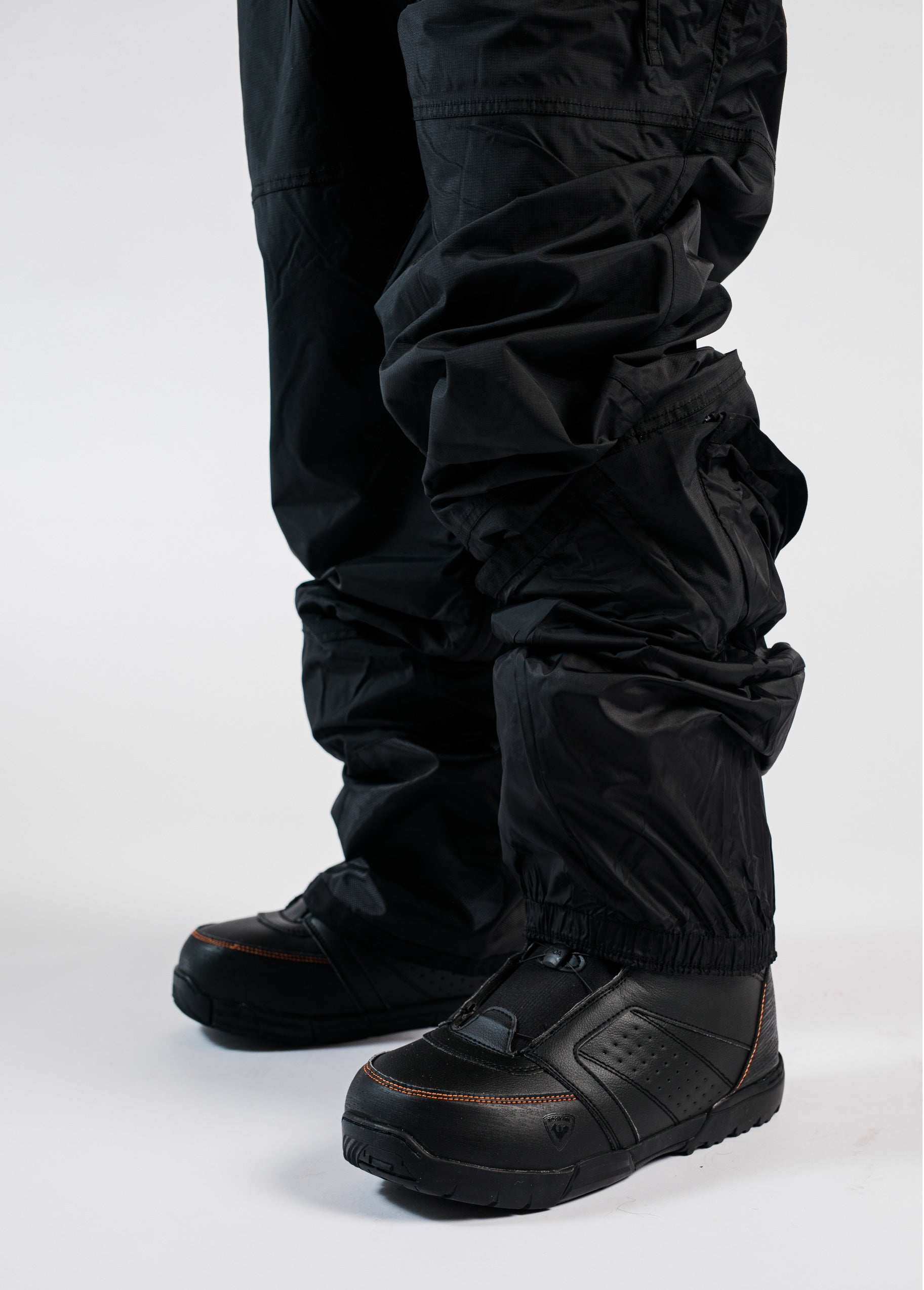Men's black snowboard bib worn over snowboard boots