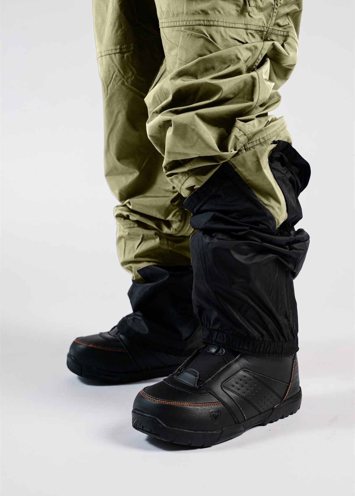 Men’s green Bloom Rove snowboard bib showing elastic boot gaiters fitted over black snowboard boots.
