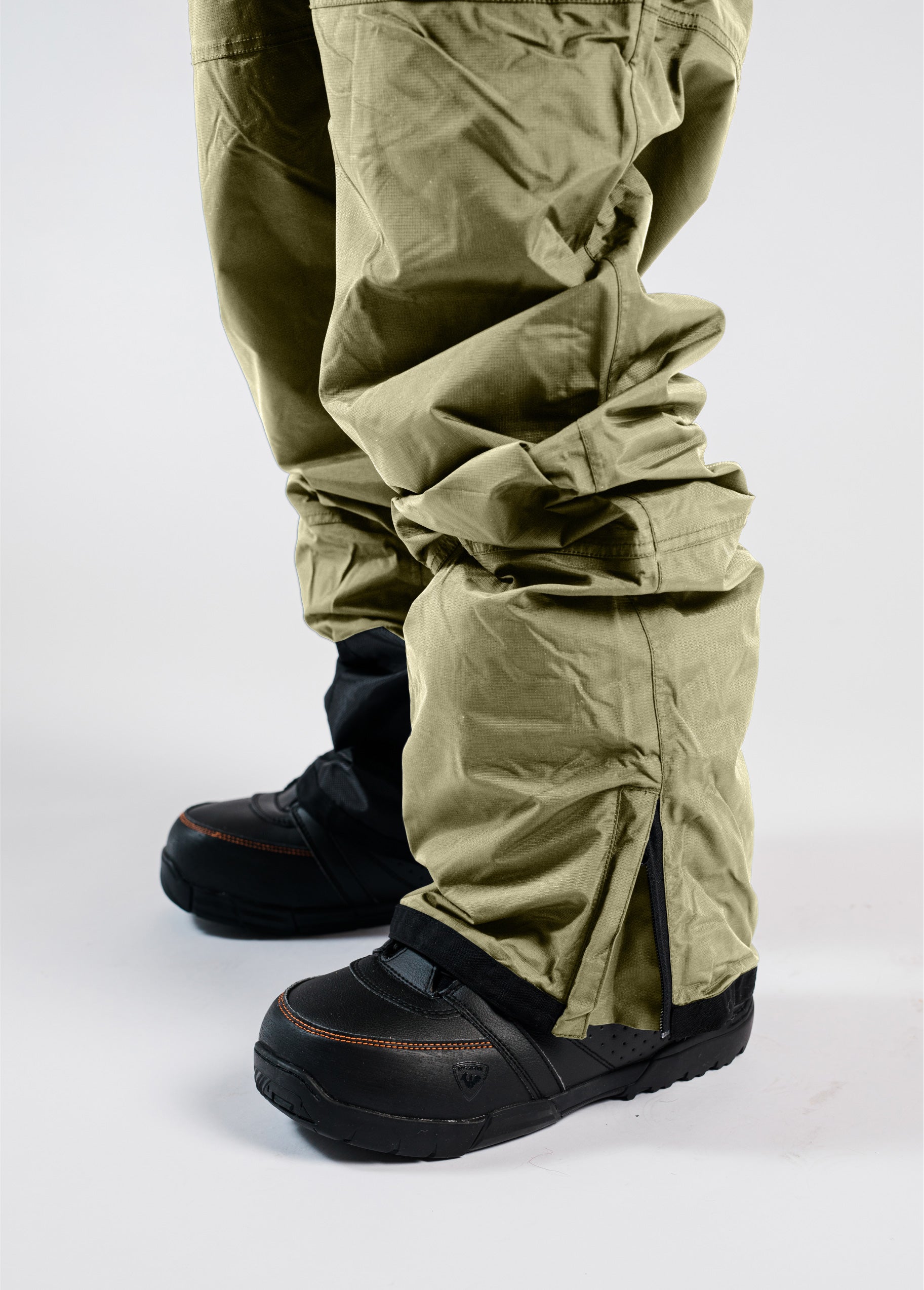 Men’s green Bloom Rove snowboard bib with the zippered hem gusset open over black snowboard boots.