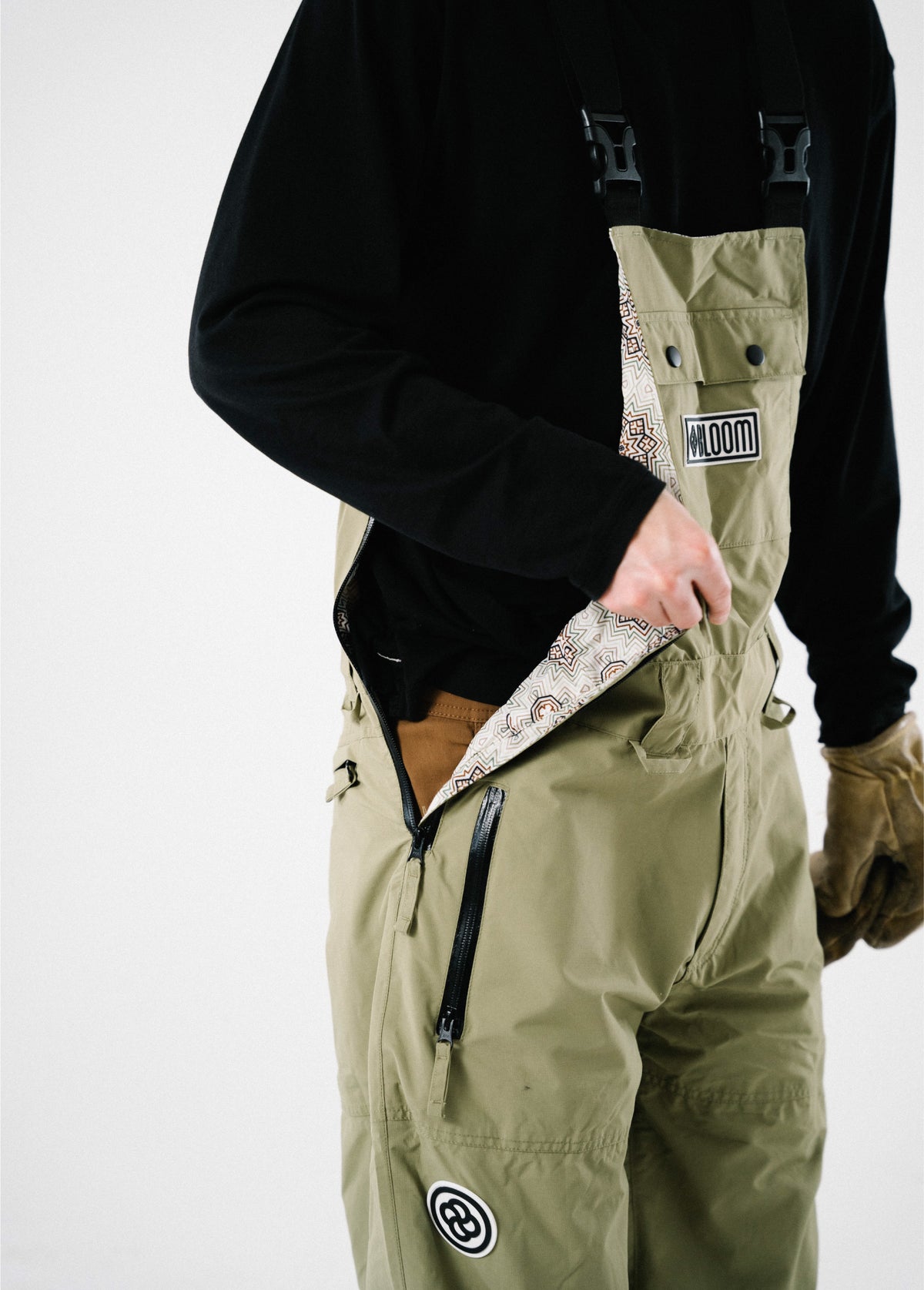 Men’s green Bloom Rove snowboard bib showing an unzipped side entry, printed liner, and waterproof pocket.
