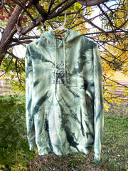 A moss green spiral tie dye hoodie with autumn backdrop