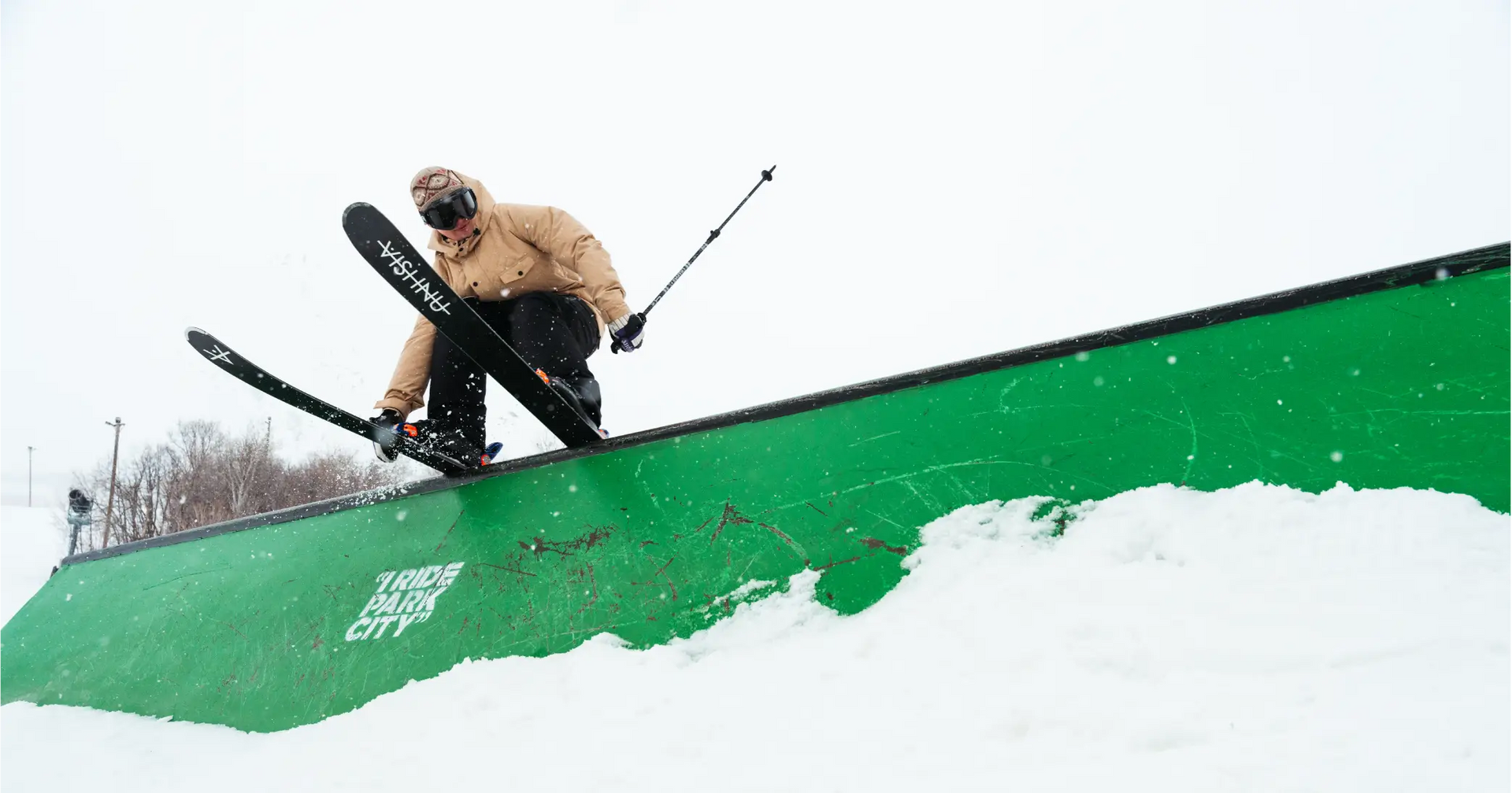 A park skier slides  rail wearing a cool quilted ski jacket