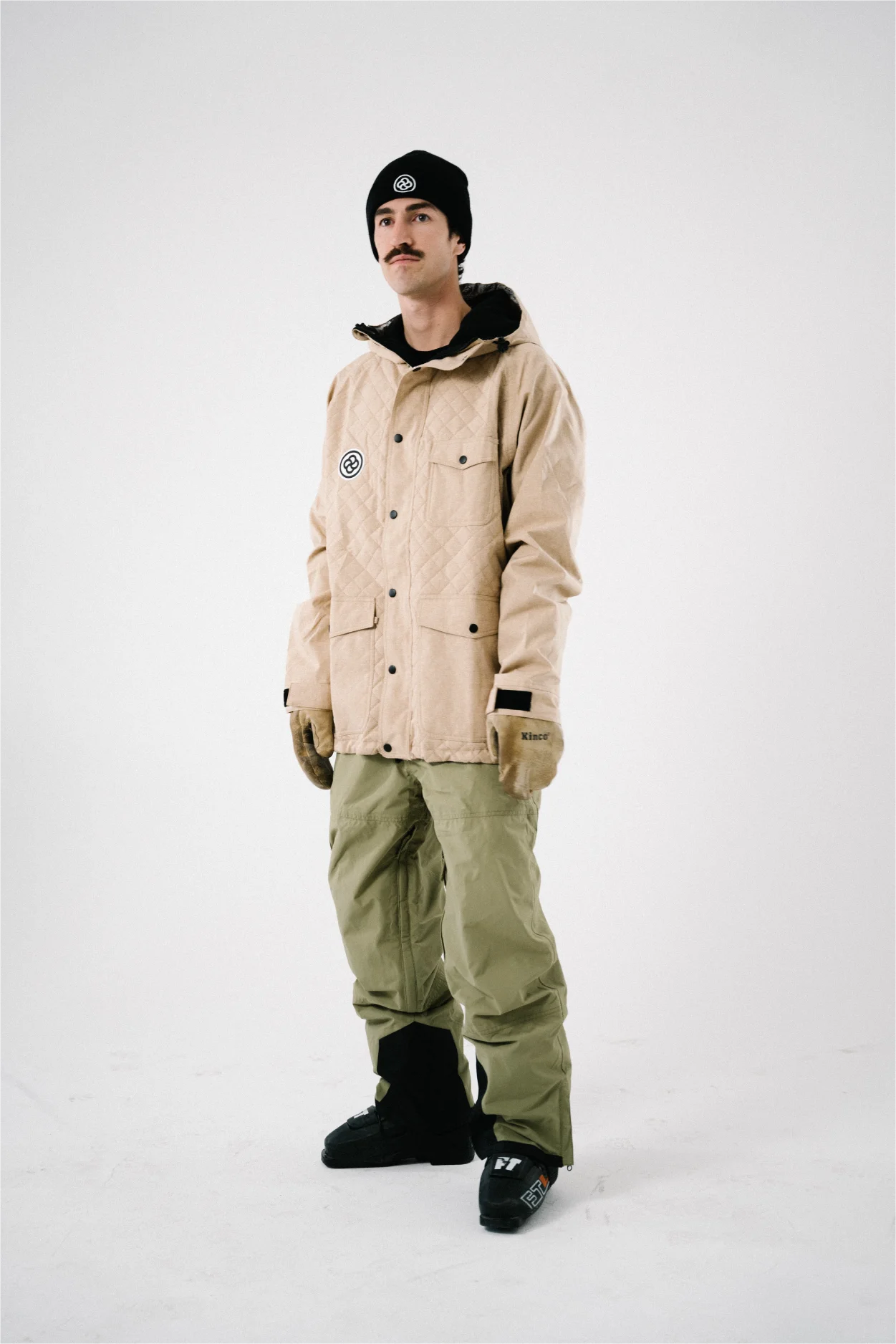 Man wearing a tan quilted snowboard jacket